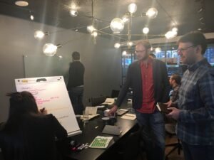 A group of colleagues in a conference room, where Jesse presents marketing strategy