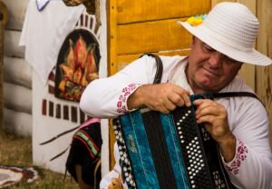 A person in a white embroidered shirt and hat working on an accordion. Photo by Andy Cat on Unsplash